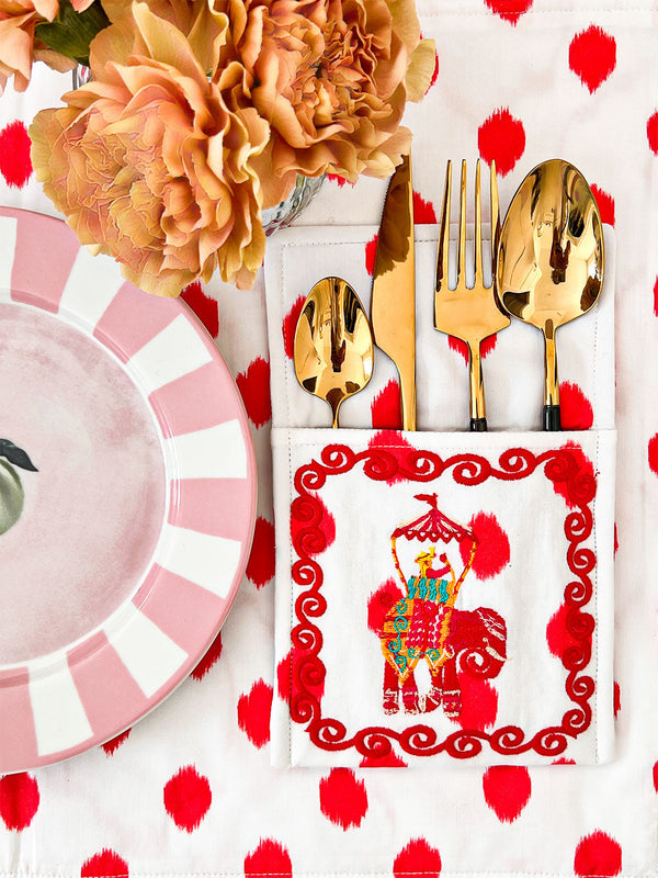 Elegant table setting with gold cutlery and embroidered fabric bags