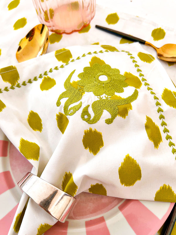 Detailed close-up of artisanal bird embroidery on green dot cotton