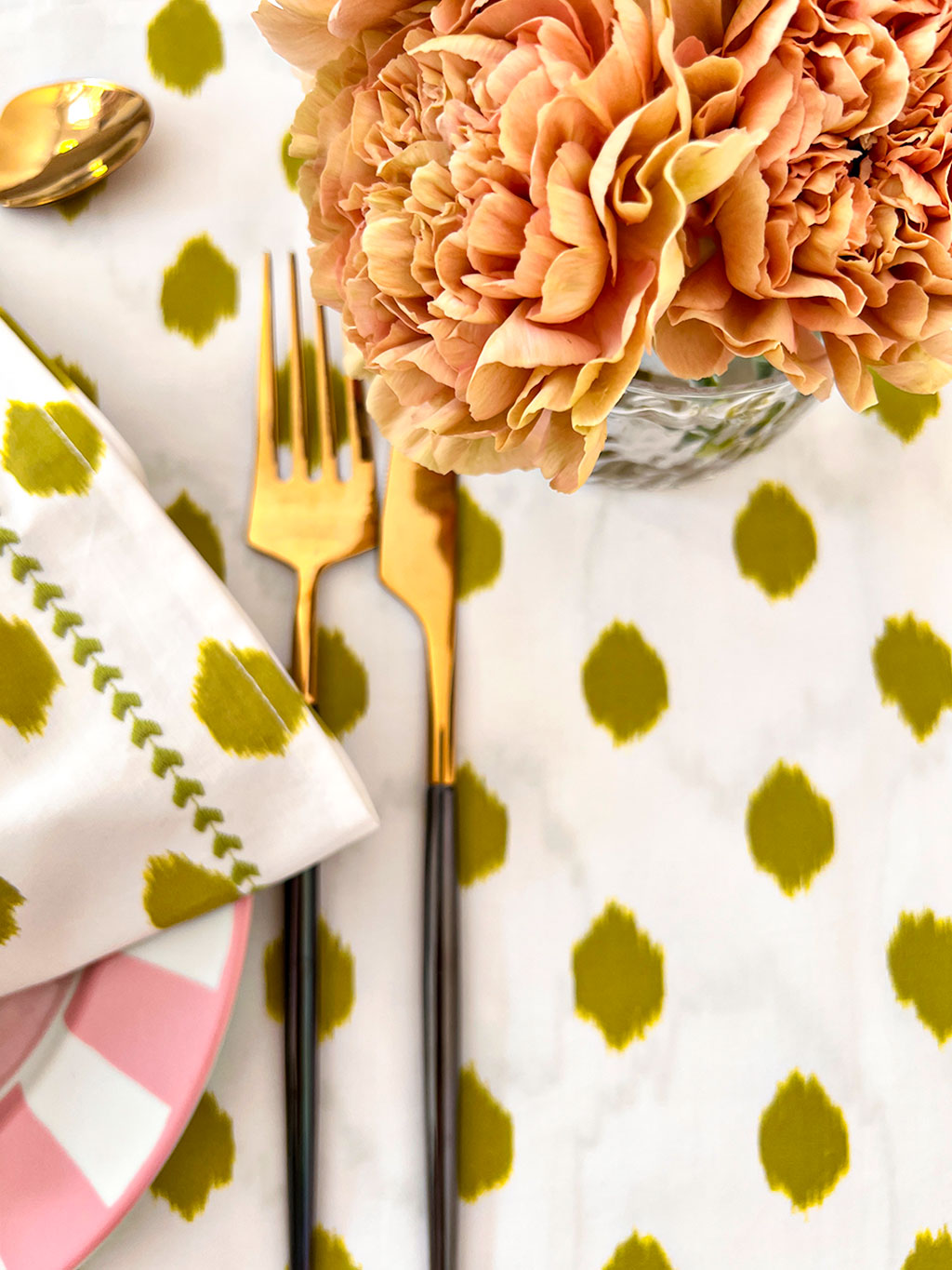 Close-up of tactile hand-embroidery and green ikat dot print